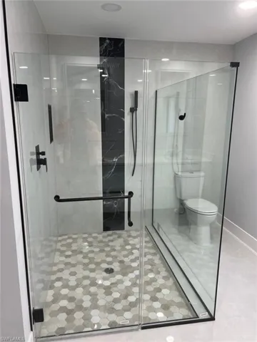 Bathroom featuring toilet and a shower with shower door