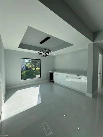 Unfurnished living room featuring a raised ceiling and beverage cooler