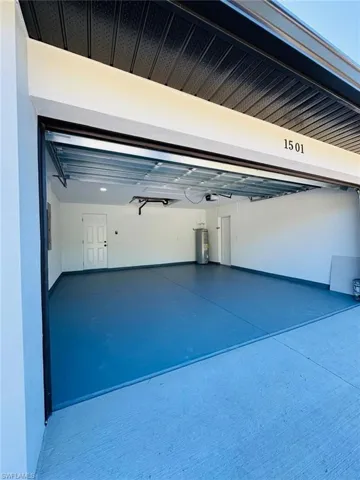 Garage featuring electric water heater and a garage door opener
