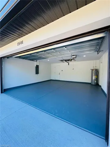 Garage with electric panel, electric water heater, and a garage door opener