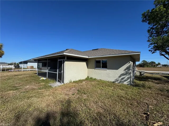View of side of home with a sunroom and a yard