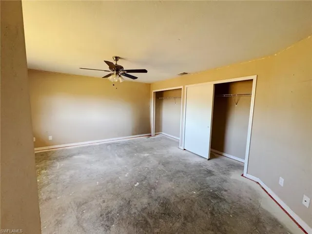 Unfurnished bedroom featuring multiple closets, ceiling fan, and concrete floors