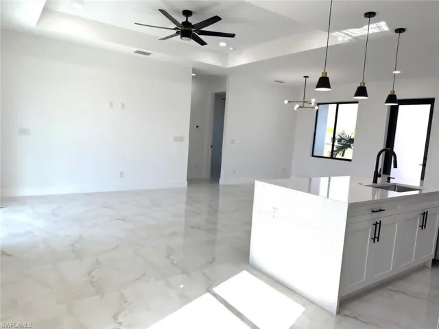 Kitchen featuring open floor plan, a tray ceiling, light marble finish flooring, and recessed lighting
