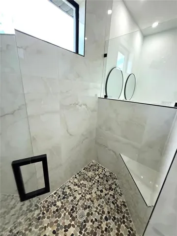 Full bath with a marble finish shower