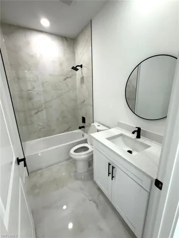 Bathroom with vanity, a combined bath / shower with marble appearance, light marble finish floors, and recessed lighting