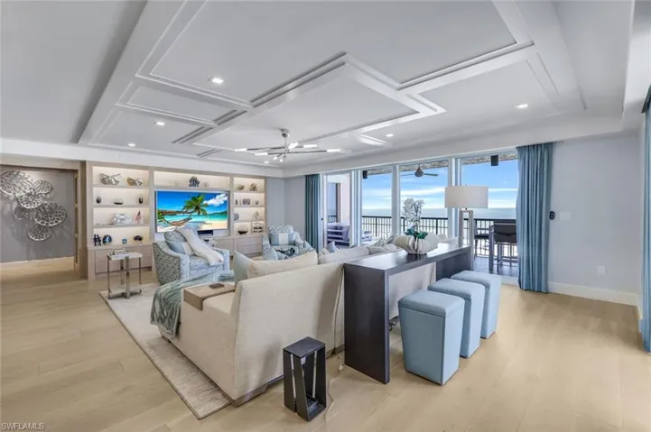 Living room featuring light hardwood / wood-style flooring, built in features, coffered ceiling, and ceiling fan