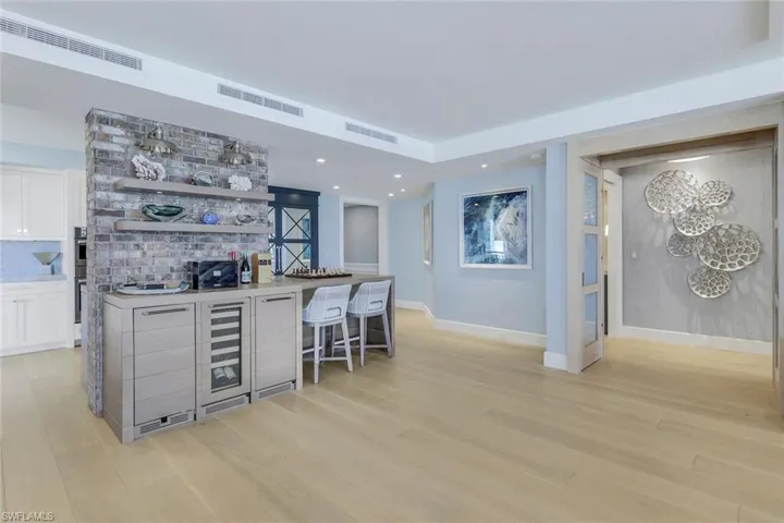 Bar featuring backsplash, white cabinetry, and light hardwood / wood-style floors