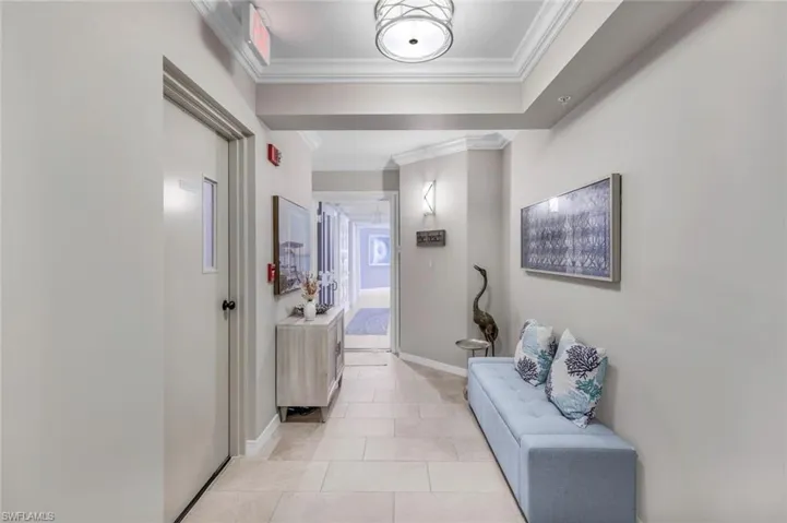 Hall featuring light tile patterned floors and ornamental molding