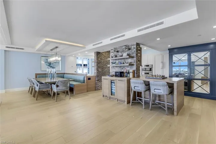 Kitchen with a breakfast bar area, white cabinetry, hanging light fixtures, and light hardwood / wood-style floors