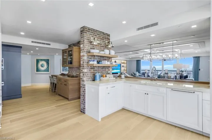 Kitchen with light hardwood / wood-style floors, decorative light fixtures, sink, and white cabinetry