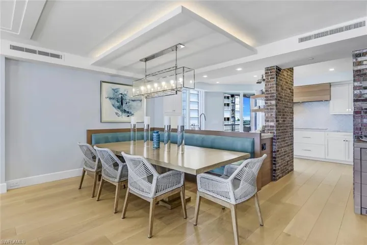 Dining area with a notable chandelier, light hardwood / wood-style flooring, and brick wall