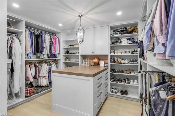 Spacious closet featuring a notable chandelier and light wood-type flooring