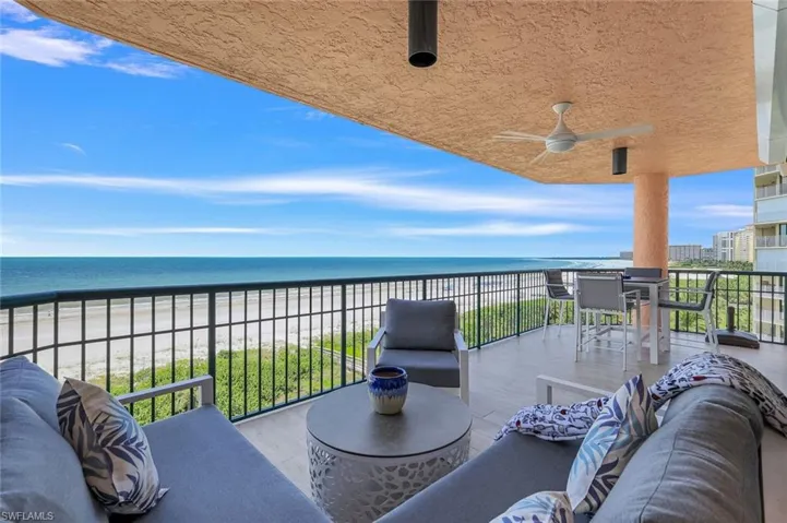 Balcony with a water view, a view of the beach, and ceiling fan