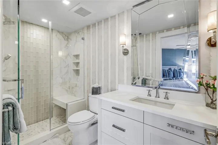Bathroom with ceiling fan, toilet, vanity, tile patterned flooring, and a shower with shower door