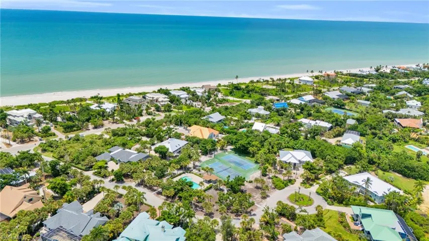 Coastal community featuring white sand beaches, turquoise waters, lush tropical landscaping, and residential properties