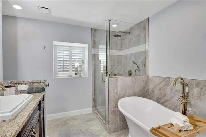 Bathroom featuring separate shower and tub and vanity
