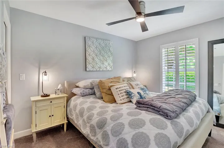 Bedroom with ceiling fan and dark colored carpet