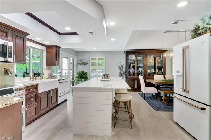 Kitchen featuring decorative light fixtures, a kitchen breakfast bar, sink, light stone countertops, and appliances with stainless steel finishes