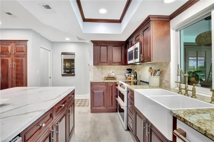 Kitchen featuring crown molding, white electric range, backsplash, sink, and a tray ceiling