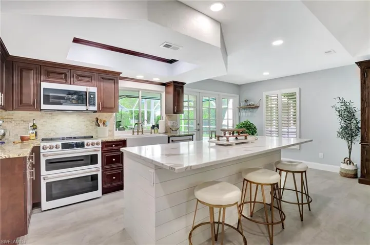 Kitchen with a kitchen island, light stone countertops, stainless steel appliances, sink, and a healthy amount of sunlight