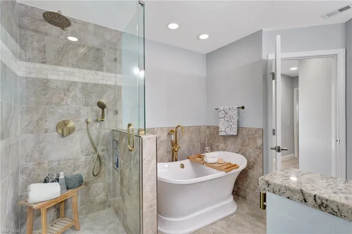 Bathroom with tile walls and plus walk in shower