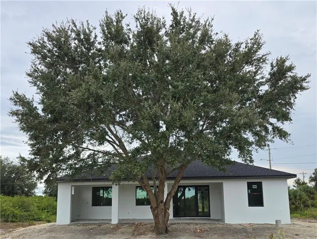 Rear view of property with a patio area, stucco siding, and a shingled roof