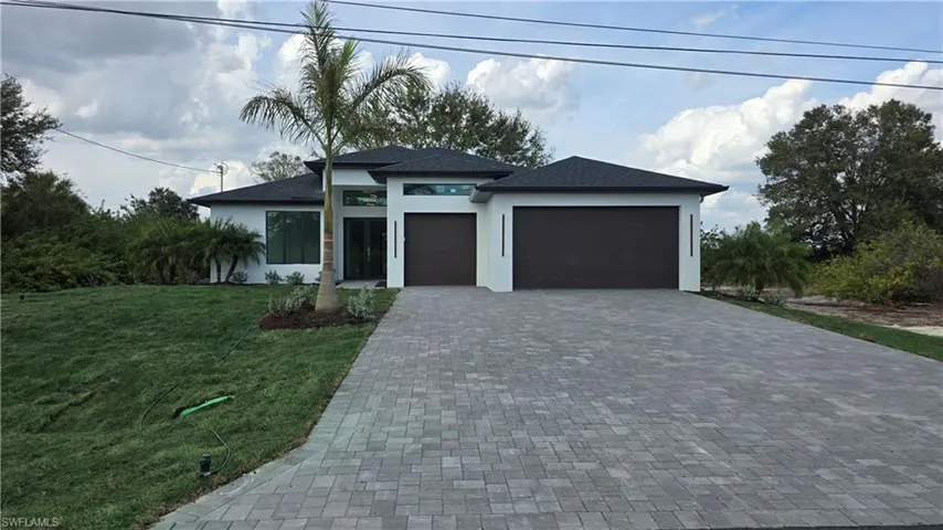 Prairie-style house featuring an attached 3+ garage, a front yard, decorative driveway, and stucco siding