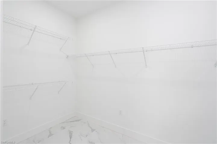 Walk in closet featuring light marble finish floors