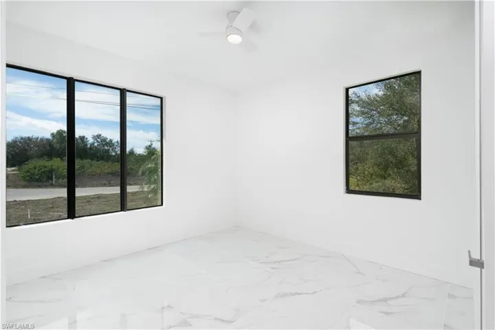 Unfurnished room featuring ceiling fan and light marble finish floors