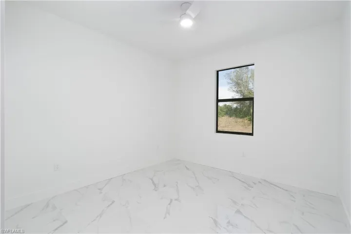 Empty room featuring light marble finish floors and a ceiling fan