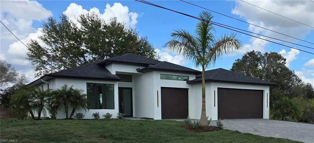 View of front of home with a front yard, stucco siding, roof with shingles, and an attached garage