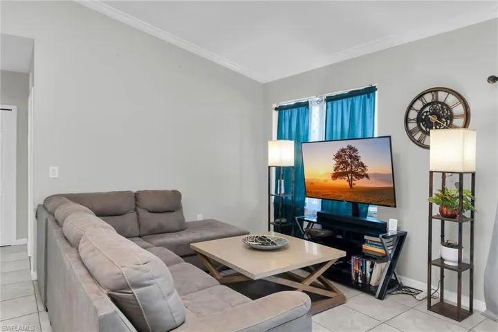 Living area featuring crown molding and light tile patterned flooring