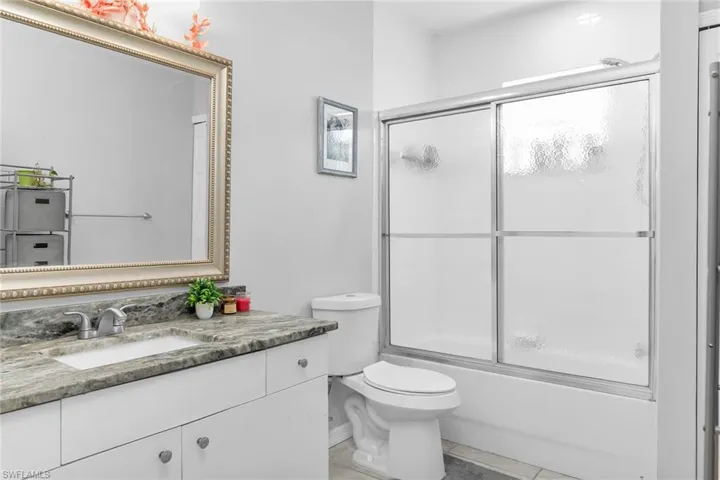 Full bathroom featuring vanity, enclosed tub / shower combo, and light tile patterned floors