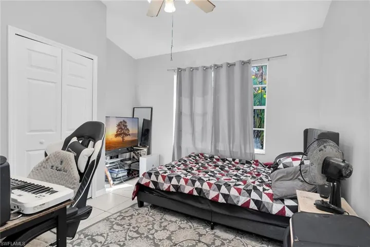 Bedroom with lofted ceiling, tile patterned floors, and ceiling fan