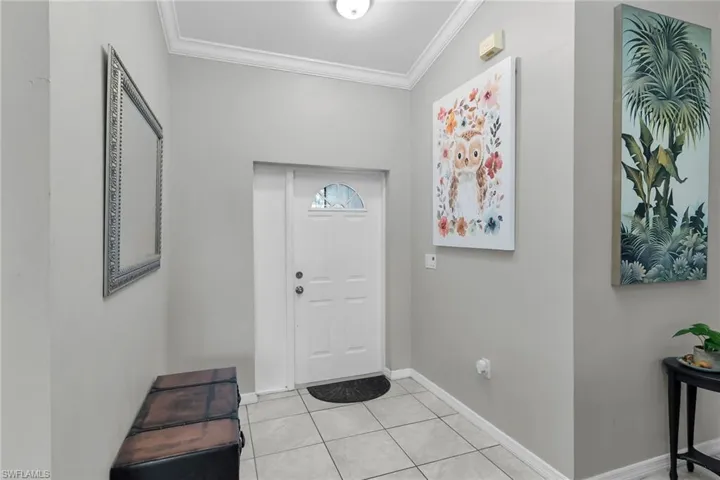Foyer with ornamental molding and light tile patterned flooring