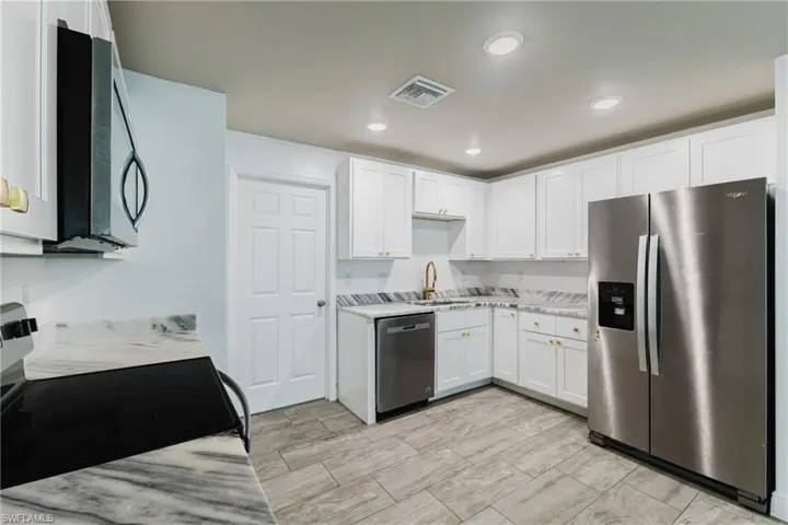 Kitchen with stainless steel appliances, white cabinets, and recessed lighting