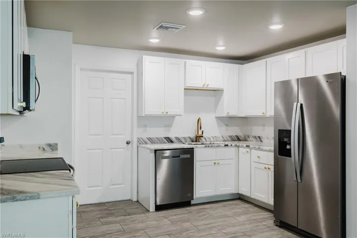 Kitchen featuring stainless steel appliances, white cabinets, wood tiled floors, and recessed lighting