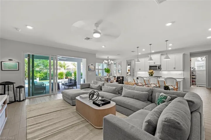 Living area with a ceiling fan, recessed lighting, wood finish floors, healthy amount of natural light, and a chandelier