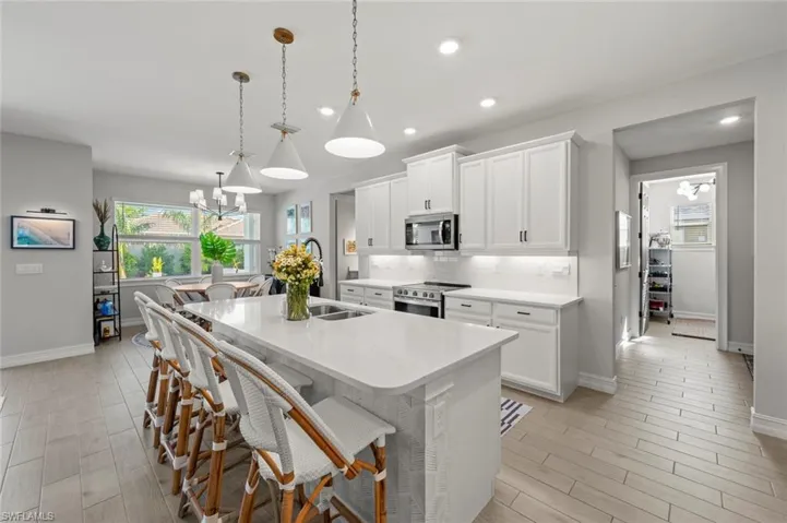 Kitchen featuring a chandelier, white cabinetry, a breakfast bar area, an island with sink, and decorative light fixtures