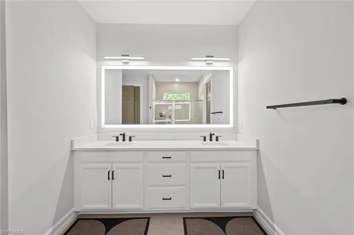 Full bathroom featuring double vanity and a shower with door