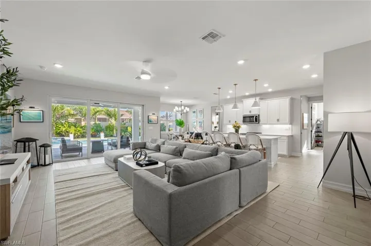 Living area featuring wood tiled floors, a chandelier, ceiling fan, healthy amount of natural light, and recessed lighting