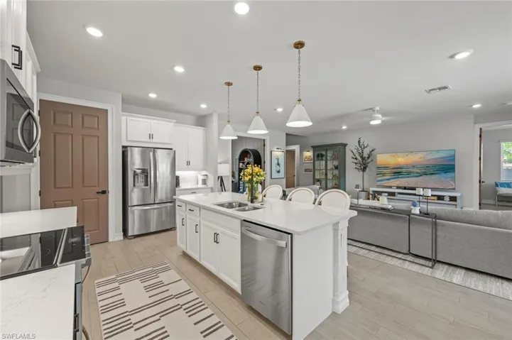 Kitchen featuring hanging light fixtures, open floor plan, appliances with stainless steel finishes, white cabinetry, and recessed lighting