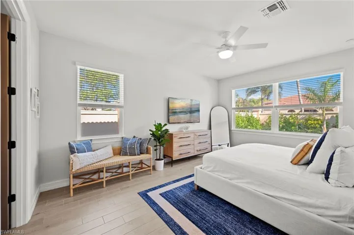 Bedroom with light wood finished floors, ceiling fan, and multiple windows