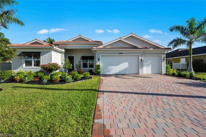 Ranch-style house featuring stucco siding, decorative driveway, a front yard, an attached garage, and a tile roof