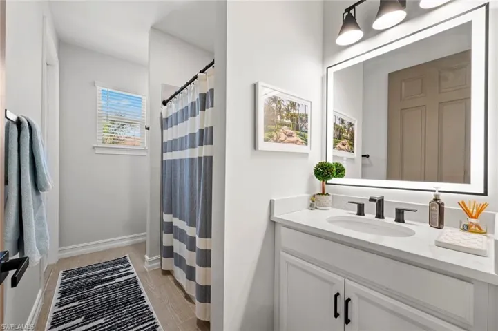 Bathroom featuring a shower with curtain, vanity, and light wood-type flooring