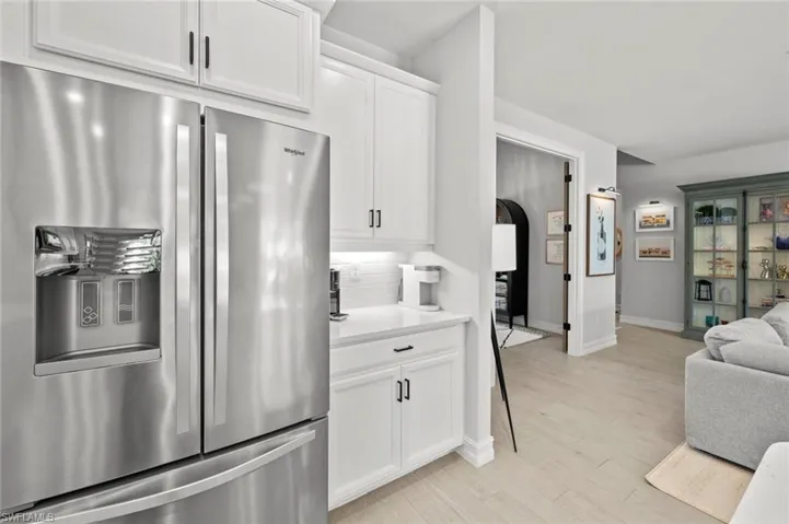 Kitchen featuring stainless steel refrigerator with ice dispenser, white cabinetry, open floor plan, and tasteful backsplash