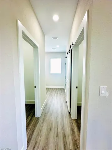 Hallway with a barn door, a textured wall, and light wood-style floors