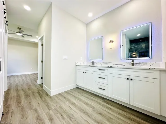 Bathroom featuring double vanity, light wood-style flooring, ceiling fan, and recessed lighting