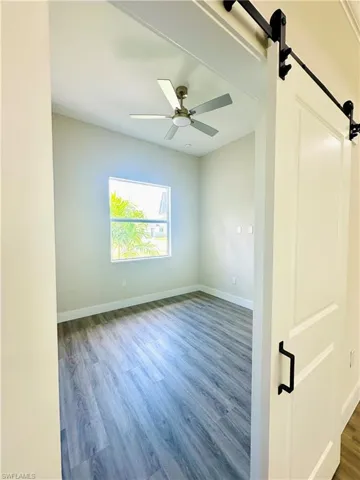 Den - Empty room with wood finished floors and a barn door