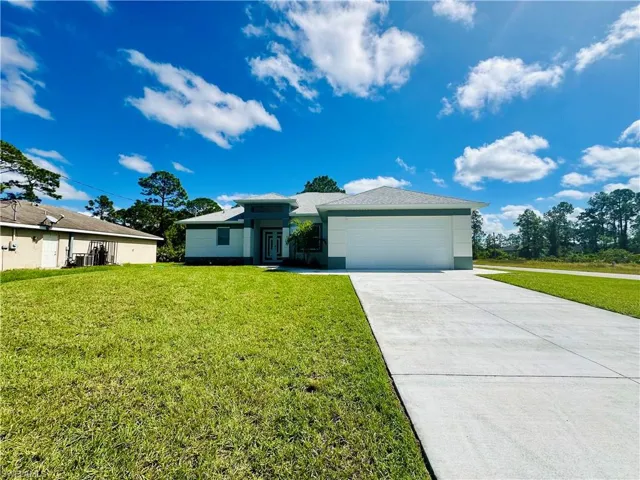 View of front facade featuring driveway, a front lawn, and a garage